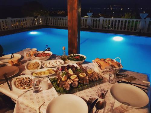 a table with food on it with a pool in the background at Ciftlik Hotel in Çeşme