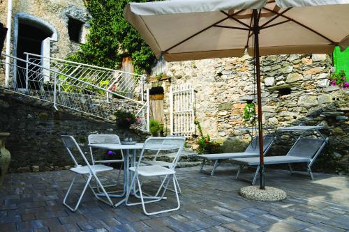 eine Terrasse mit einem Tisch, Stühlen und einem Sonnenschirm in der Unterkunft Agriturismo Nonnamelia in Nasino