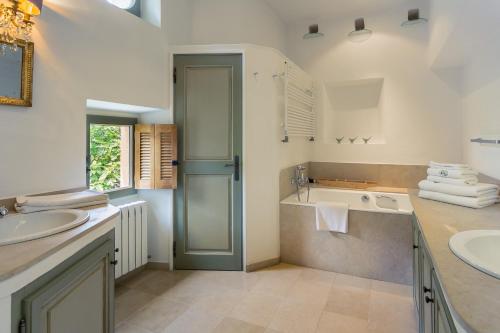 a bathroom with two sinks and a tub and a shower at La Ferme du Haut Trigaud in Bonnieux