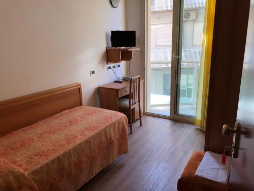 een slaapkamer met een bed, een televisie en een raam bij Hotel Bamar in Cervia