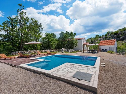 una piscina en un patio con sillas y sombrilla en Bonaventura Countryside Villa near Split, en Neorić