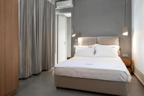 una camera da letto con un grande letto con lenzuola e cuscini bianchi di Elisa Seaside Luxury Suite a Loutraki