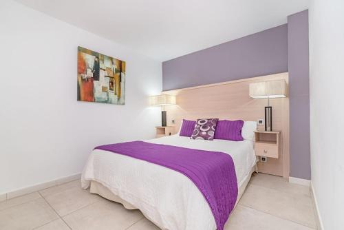 a bedroom with a large bed with purple sheets at Sol Mogan Suites - Adults Only in Puerto de Mogán
