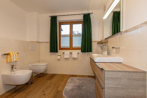 een badkamer met een wastafel, een toilet en een raam bij Ferienhaus STOARÖSERL in Mittenwald