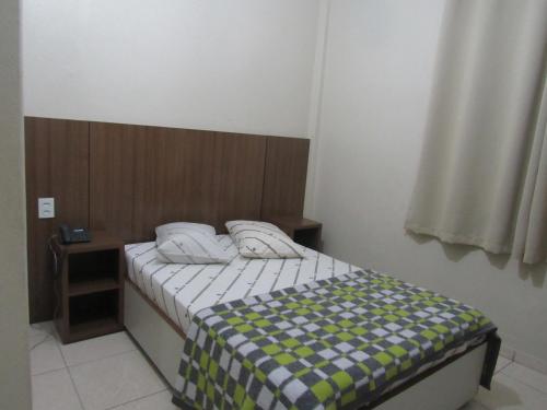 a small bedroom with a bed with a checkered blanket at Hotel Moraes a 10 minutos da 25 de Março,Brás,Bom Retiro,a 2 minutos do Mirante Sampa Sky e pista de Skate Anhangabaú in Sao Paulo