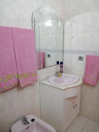 a bathroom with a sink and a mirror and a toilet at Quartos Lazarino in Nazaré