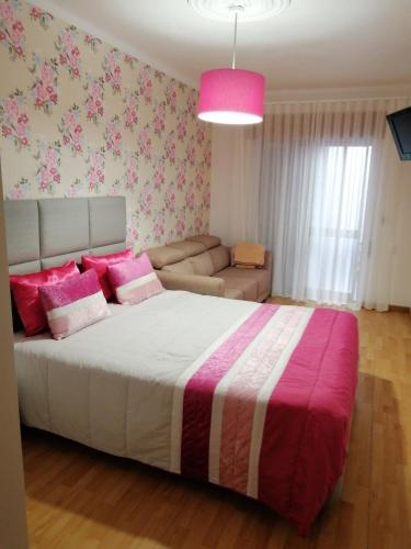 a bedroom with a large bed with pink pillows at Quartos Lazarino in Nazaré