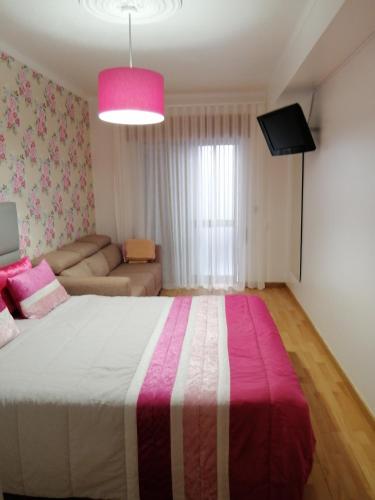 a bedroom with a large bed with a pink blanket at Quartos Lazarino in Nazaré