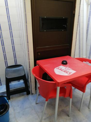a red table with a red chair and a red table at Quartos Lazarino in Nazaré