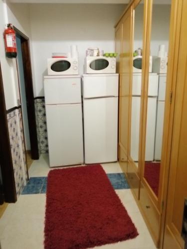 a laundry room with washers and dryers and a red rug at Quartos Lazarino in Nazaré