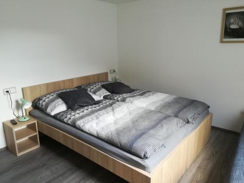 1 cama con marco de madera en un dormitorio en Penzion Šápara, en Velké Bílovice