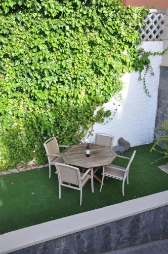 stół i krzesła na trawniku z żywopłotem w obiekcie Villa Alegria w mieście Santa Brígida