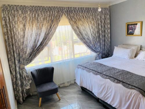 a bedroom with a bed and a chair and a window at River Valley Guest House in Butterworth
