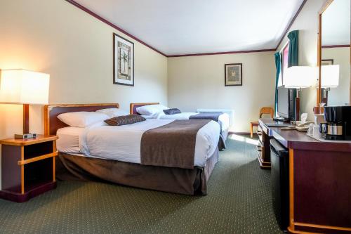 a hotel room with two beds and a flat screen tv at Creston Hotel & Suites in Creston