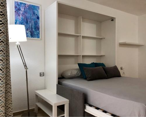 a bedroom with a bed and a lamp and shelves at Castillo Santa Clara in Torremolinos