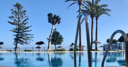 a large pool of water with palm trees at Castillo Santa Clara in Torremolinos
