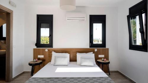 sypialnia z białym łóżkiem z dwoma stołami w obiekcie Kiotari Akti Beachfront Villas w mieście Jenadi