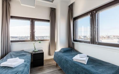 two beds in a room with two windows at Sky Hostel Helsinki in Helsinki