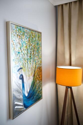 a painting of a peacock on a wall next to a lamp at Maniu 31 Apartments & Rooms in Oradea