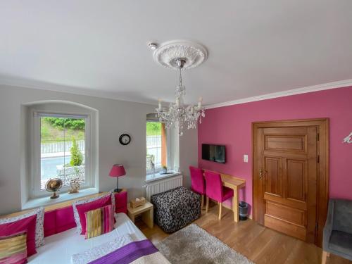 a living room with pink walls and a chandelier at Pension Oybin in Kurort Oybin