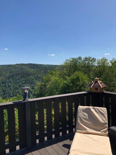 a chair on a balcony with a view of the mountains at Bungalow Schwarzatalblick in Bad Blankenburg Ortsteil Böhlscheiben in Bad Blankenburg