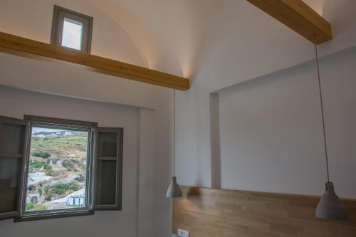 a living room with a window and a staircase at Amphitrite Suites Santorini in Vóthon