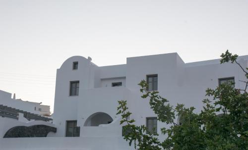 a white building with a tree in front of it at Amphitrite Suites Santorini in Vóthon