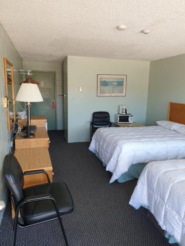 Cochrane的住宿－Chimo Motel，酒店客房 - 带两张床、一张桌子和一把椅子