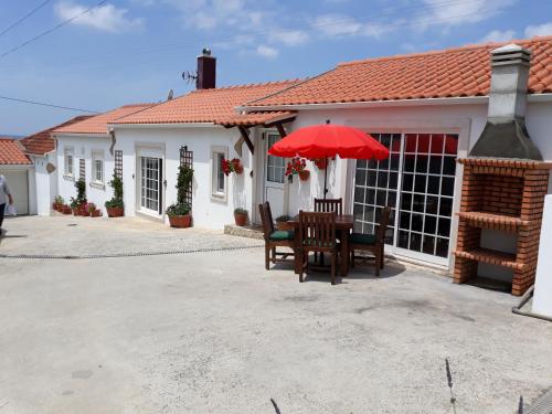 a table with a red umbrella in front of a house at Casa Branca do Moinho in Salgueiro