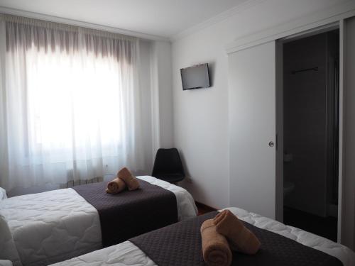 a hotel room with two beds and a window at PR Una Estrella Dorada in O Pedrouzo