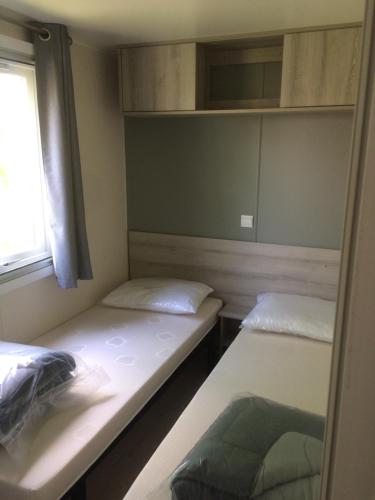 two beds in a small room with a window at MOBIL HOME 6/8 places in Onzain