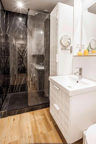 une salle de bain avec un lavabo blanc et une douche dans l'établissement Homard and Fox, Appartement 2 chambres 100m de la mer, à Dinard