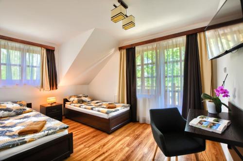 a hotel room with two beds and a desk at Agroturystyka Olszynka in Skopanie