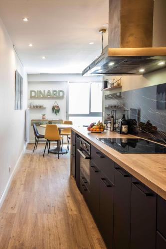 une cuisine avec des armoires noires et une salle à manger dans l'établissement Homard and Fox, Appartement 2 chambres 100m de la mer, à Dinard