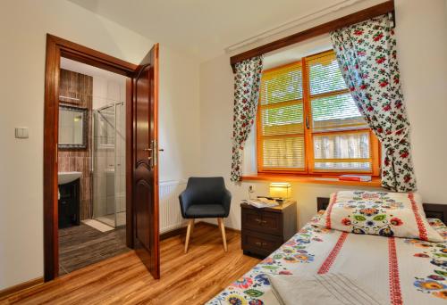 a bedroom with a bed and a chair and a window at Agroturystyka Olszynka in Skopanie