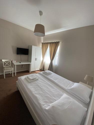 a bedroom with a large white bed and a desk at B&B Andero Deva in Deva