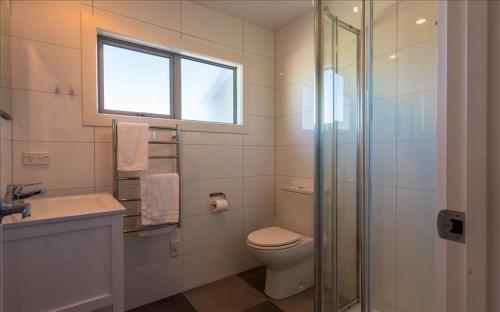 a bathroom with a toilet and a sink and a window at THE WAIHEKE PAD - in the heart of Oneroa! - Be My Guest Waiheke in Oneroa