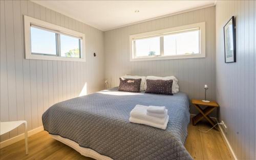 a bedroom with a large bed with two windows at THE WAIHEKE PAD - in the heart of Oneroa! - Be My Guest Waiheke in Oneroa