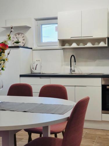 a kitchen with a table and red chairs at Apartman Školj in Jovići