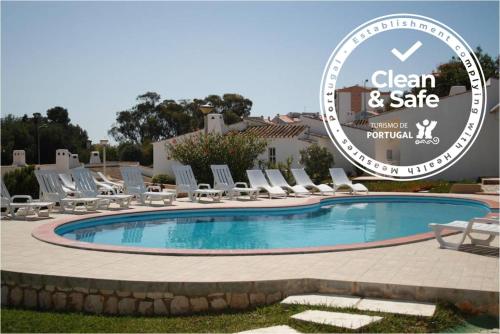 a pool with chairs and a sign in front of it at Apartamentos Turisticos Marsol in Lagos