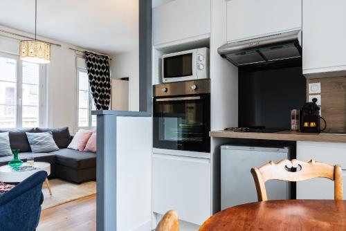 uma cozinha e sala de estar com um sofá e uma mesa em TOWNHOUSE TROUVILLE - Appart'Hotel & Studios em Trouville-sur-Mer