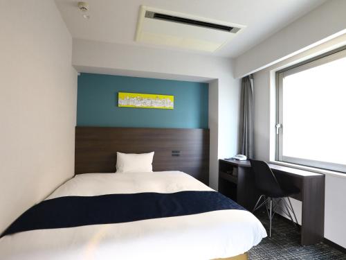a bedroom with a bed and a desk and a window at Hotel Wing International Ikebukuro in Tokyo