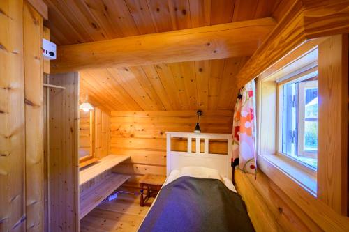 Blockhütte mit einem Bett und einem Fenster in der Unterkunft Rondane River Lodge - Rondane Gjestegård in Enden