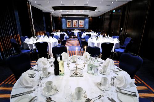 a room with tables and chairs with white tablecloths at Crowne Plaza London - Gatwick Airport by IHG in Crawley