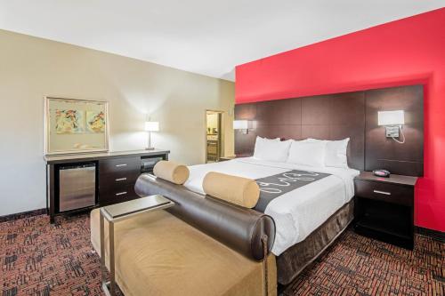a large bed in a hotel room with a red wall at La Quinta by Wyndham Elk City in Elk City