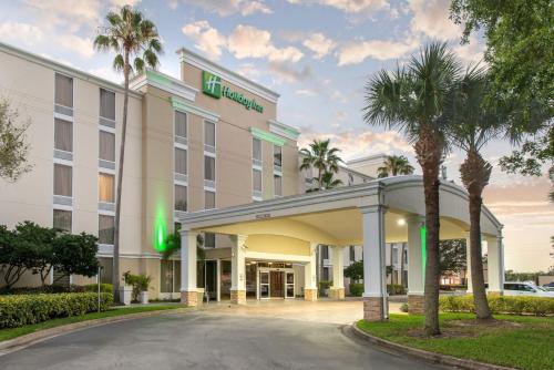 an exterior view of a hotel with palm trees at Holiday Inn Melbourne-Viera Conference Ctr by IHG in Melbourne