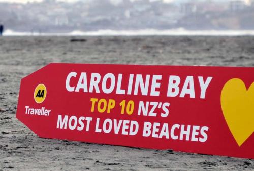 a red sign on the beach with the ocean in the background at Panorama Motor Lodge in Timaru