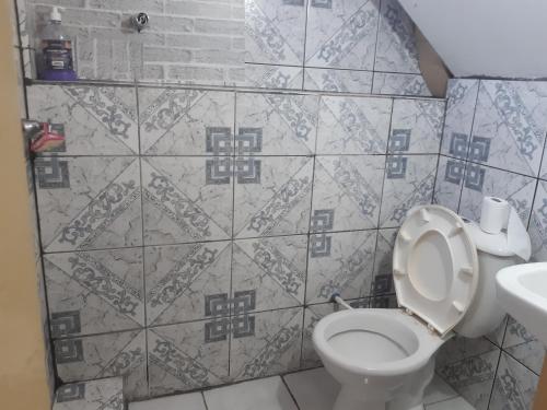 a bathroom with a toilet and a tile wall at Pousada do Luquinhas in Brasilia