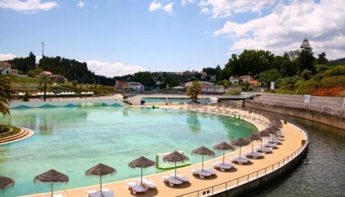 a swimming pool with umbrellas and chairs and water at Casa Sandra - Apartamento Mariana in Lousã