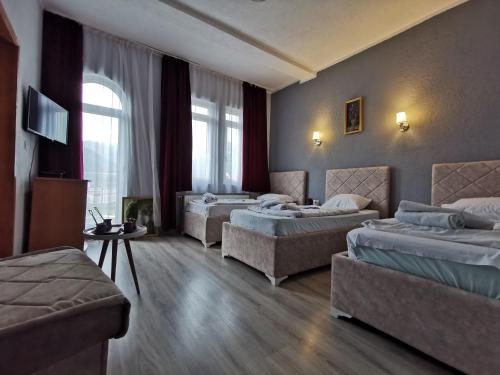 a hotel room with three beds and a tv at Hotel Rosi in Gusinje